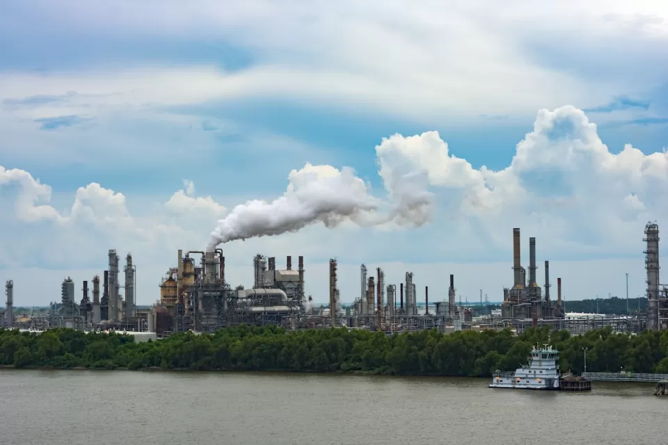 Cheical plant with shite steam coming out of metal towers on riverbank in Louisiana.